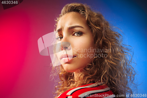 Image of The serious sad woman standing and looking at camera against colorful background.