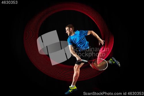 Image of one caucasian man playing tennis player on black background