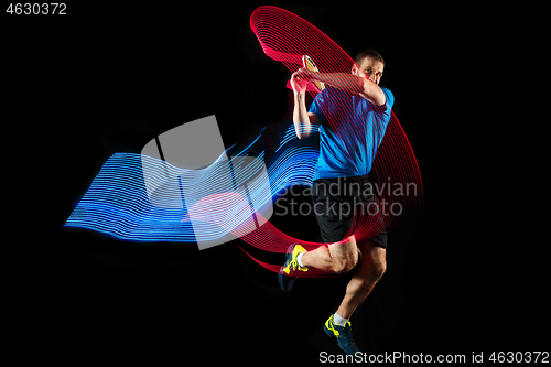 Image of one caucasian man playing tennis player on black background