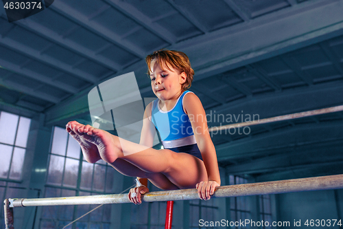 Image of beautiful girl is engaged in sports gymnastics on a parallel bars