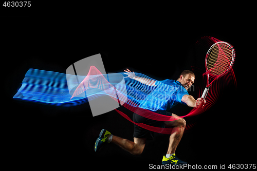 Image of one caucasian man playing tennis player on black background