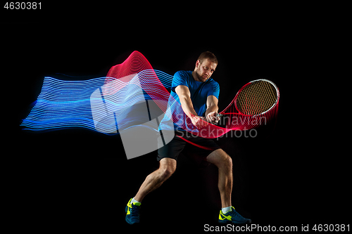 Image of one caucasian man playing tennis player on black background