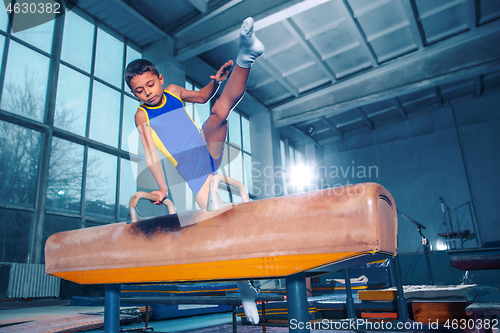 Image of The sportsman performing difficult gymnastic exercise at gym.