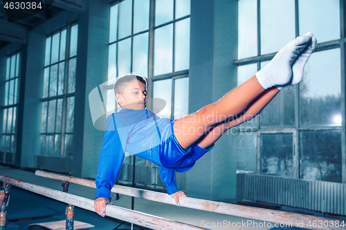 Image of beautiful boy is engaged in sports gymnastics on a parallel bars