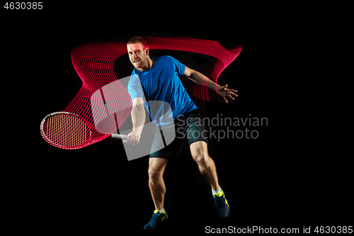 Image of one caucasian man playing tennis player on black background