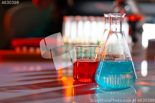 Image of Illuminated laboratory flask filed with colorful chemical solutions with shadows on the table. Laboratory, science, chemistry... consept.