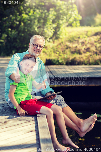 Image of grandfather and boy with tablet pc on river berth
