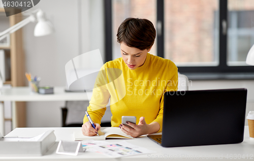 Image of smiling ui designer using smartphone at office