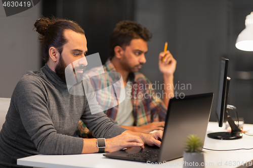 Image of creative team with computer working late at office