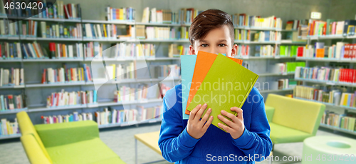 Image of shy student boy hiding behind books at library