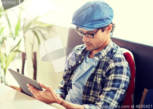 Image of man with tablet pc sitting at cafe table