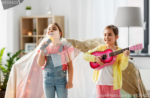 Image of girls with guitar and microphone playing at home