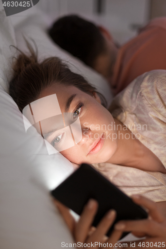 Image of woman using smartphone while boyfriend is sleeping