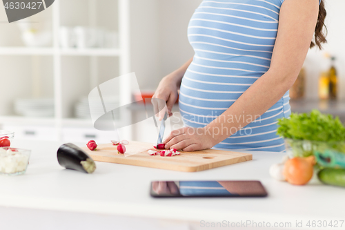 Image of close up of pregnant woman cooking food at home