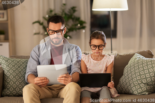 Image of father and daughter with tablet computers at home