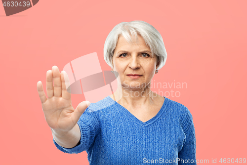 Image of senior woman in blue sweater making stop gesture