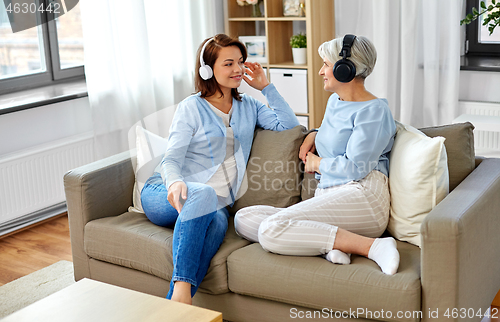 Image of senior mother and adult daughter with headphones