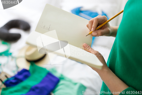 Image of woman going on trip and making list in notebook