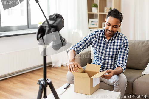 Image of male video blogger opening parcel box at home