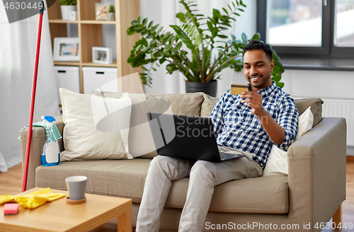 Image of man with laptop shopping online after cleaning