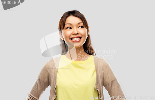 Image of happy asian woman looking up over grey background