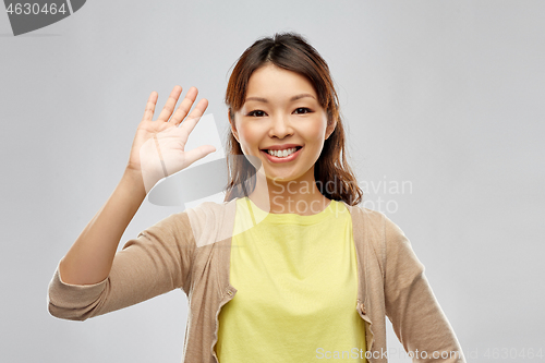 Image of happy asian woman waving hand