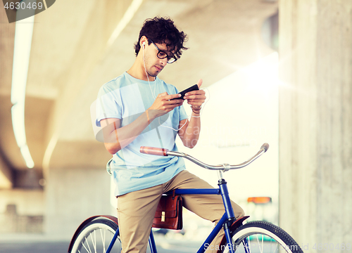 Image of man with smartphone and earphones on bicycle