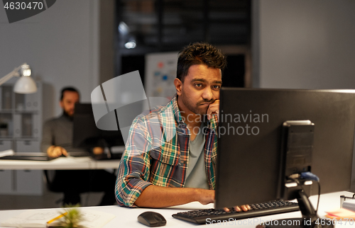 Image of creative man with computer working at night office