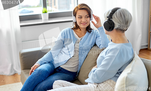 Image of senior mother and adult daughter with headphones