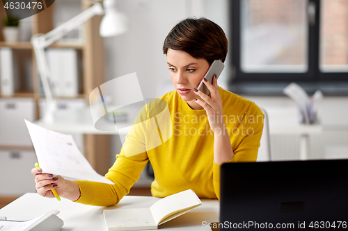 Image of businesswoman calling on smartphone at office