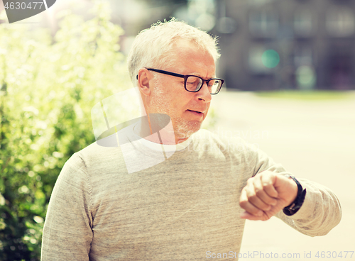 Image of senior man checking time on his wristwatch