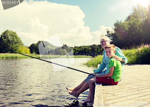 Image of grandfather and grandson fishing on river berth