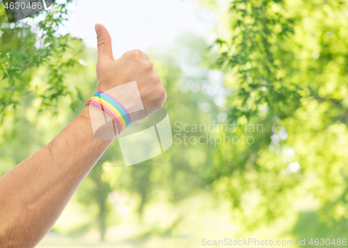 Image of hand with gay pride rainbow wristband shows thumb