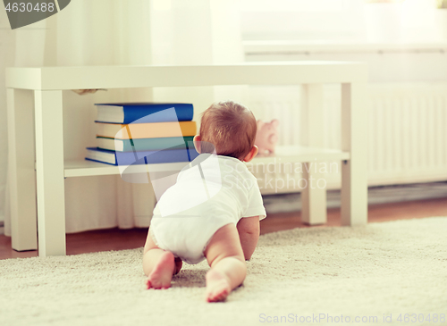 Image of little baby in diaper crawling on floor at home