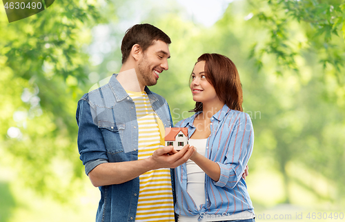 Image of smiling couple holding house model