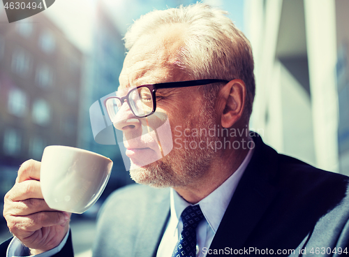 Image of senior businessman drinking coffee on city street