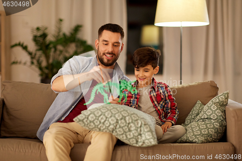 Image of father and son playing with toy dinosaur at home