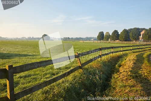 Image of Green field with fence by a village