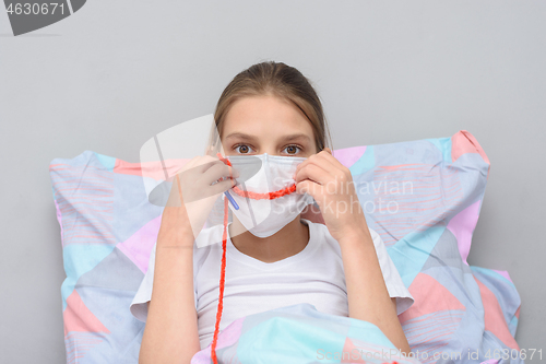 Image of Girl shows a smile on her face made of threads, doing knitting at home in self-isolation mode