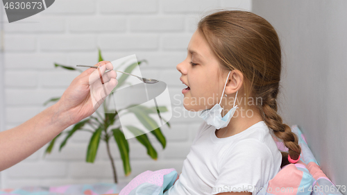 Image of A girl drinks medicine in the hospital