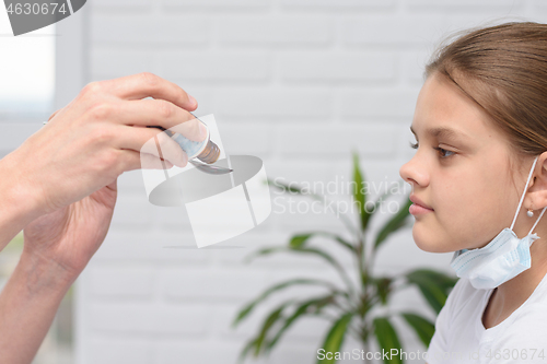 Image of The doctor in the hospital pours medicine for a sick girl in a spoon