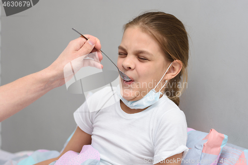 Image of Girl drinking a very nasty medicine from a spoon
