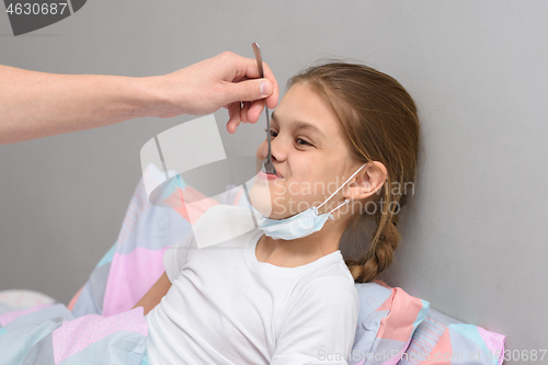 Image of A sick girl is given medicine from a spoon in her mouth