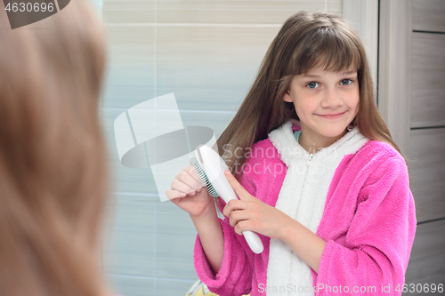 Image of Girl combing long hair at home with a comb