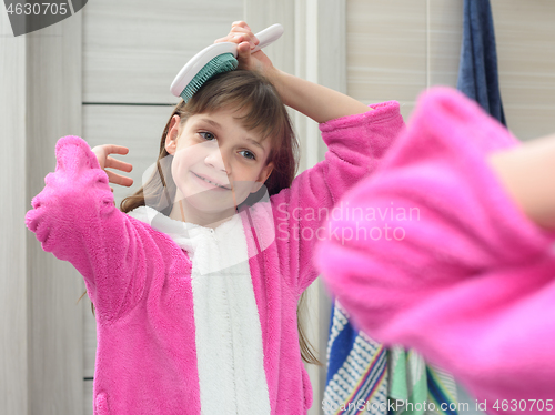 Image of Girl combing her hair in the bathroom early in the morning