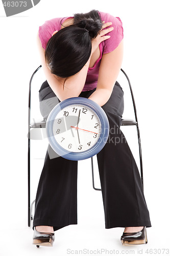 Image of Tired businesswoman holding a clock