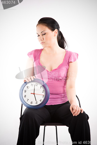 Image of Tired businesswoman holding a clock