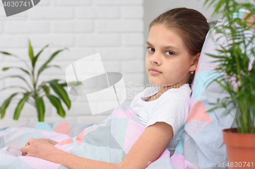 Image of Portrait of a girl lying in bed and looking at the frame