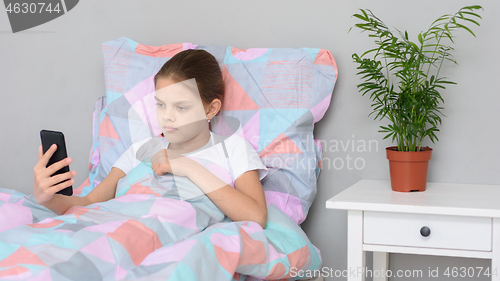 Image of Girl communicates by video calling while lying in bed with a mobile phone