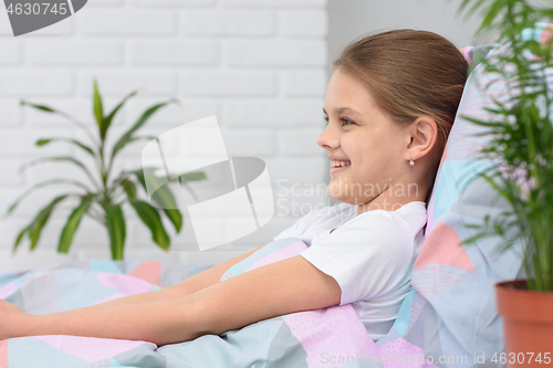 Image of Happy ten-year-old girl in the morning lies in bed and smiles